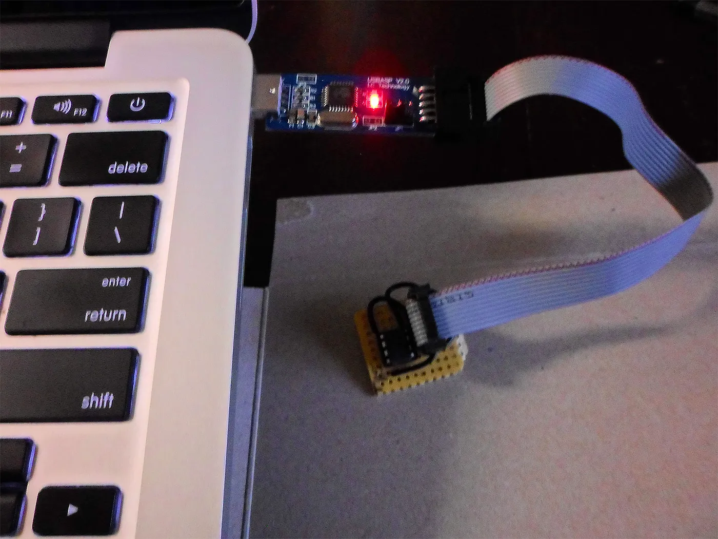 A USB programmer flashing a small breadboard circuit next to a laptop